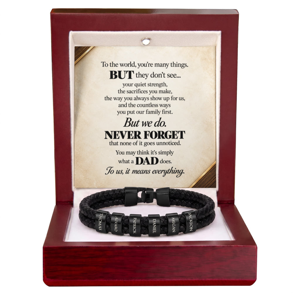 A black braided cord bracelet with silver letter beads inscribed with 'I LOVE YOU', presented inside an open dark red wooden gift box with a printed memorial message card.