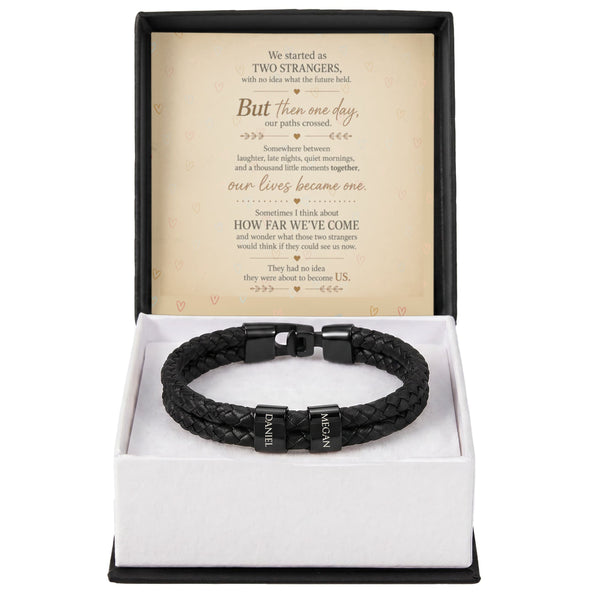 A black braided leather bracelet with a silver-toned clasp engraved with 'JANIEL' and 'ALEXANDER', presented in an open white gift box with a black outer base. The inside of the box features a sentimental message card.