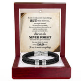 A black braided cord bracelet with silver-toned metal clasps, presented inside an open reddish-brown wooden gift box. The box contains a printed memorial-style message card addressed to a father, with the bracelet displayed below on a white insert.