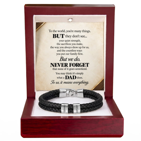 A black braided cord bracelet with silver-toned metal clasps, presented inside an open reddish-brown wooden gift box. The box contains a printed memorial-style message card addressed to a father, with the bracelet displayed below on a white insert.