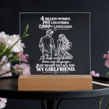 A rectangular acrylic LED light box on a wooden base, featuring white engraved text and a couple holding hands illustration. The acrylic reads, '4 BILLION WOMEN.
