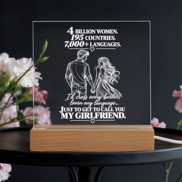 A rectangular acrylic LED light box on a wooden base, featuring white engraved text and a couple holding hands illustration. The acrylic reads, '4 BILLION WOMEN.