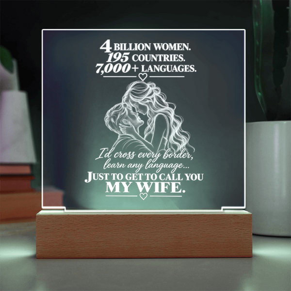 A rectangular acrylic LED light sign on a wooden base, featuring white engraved text and a line drawing of a couple embracing. The sign reads, '4 BILLION WOMEN.
