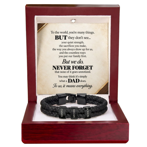 A black braided cord bracelet with three black metal name tags engraved with 'DAD', 'MATHER', and 'FATHER', presented inside an open dark red wooden gift box with a sentimental poem printed on the insert card.