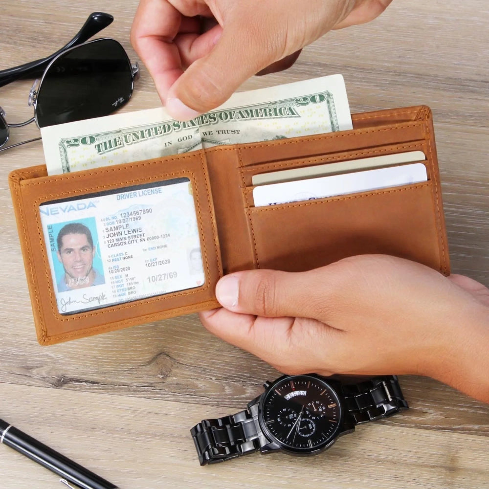 Person holding a brown leather wallet with money, cards, and an ID card on a wooden surface.