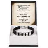 A black braided cord bracelet with silver-toned engraved beads, presented in a white box with a black outer frame. The inside lid features a printed message for Dad.