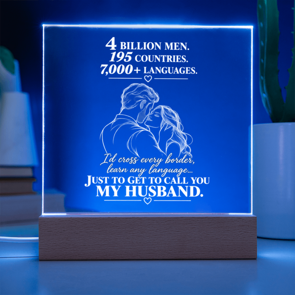 A rectangular acrylic LED lamp on a wooden base, glowing blue with white engraved text and a couple illustration. The text reads, '4 BILLION MEN.