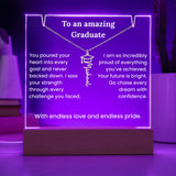 Neon sign with graduation-themed message and necklace graphic on a wooden base.