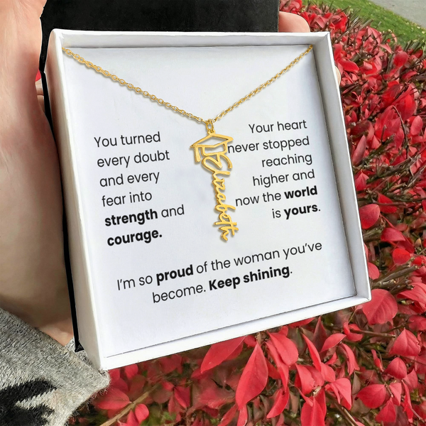 Gold necklace in a box with motivational message, held by a person outdoors.