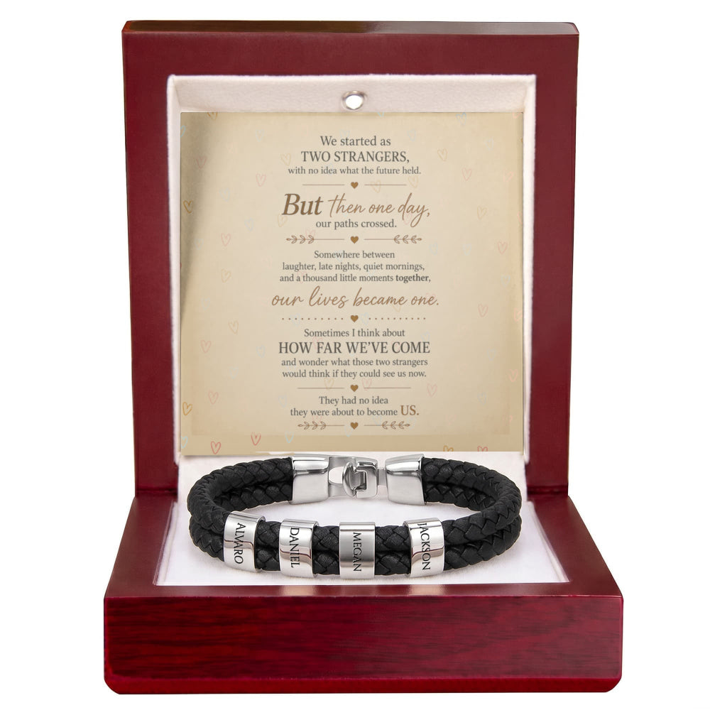A black braided leather bracelet with silver-toned metal bands engraved with 'ORION' and 'KARMA', presented inside an open dark red wooden gift box with a white insert and a printed sentimental message card.