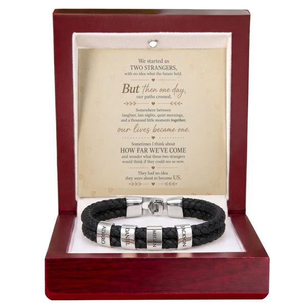 A black braided leather bracelet with silver-toned metal bands engraved with 'ORION' and 'KARMA', presented inside an open dark red wooden gift box with a white insert and a printed sentimental message card.