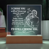 An acrylic LED light sign on a wooden base, featuring a romantic quote and an illustration of a couple from behind with hearts, displayed on a tabletop.