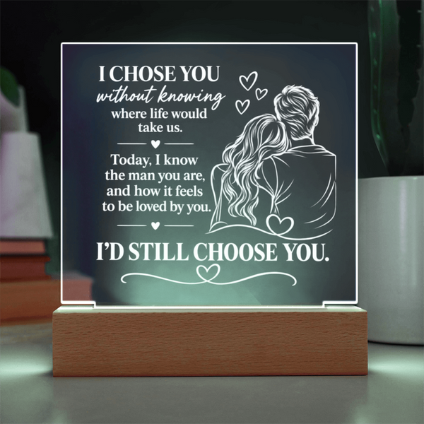 An acrylic LED light sign on a wooden base, featuring a romantic quote and an illustration of a couple from behind with hearts, displayed on a tabletop.