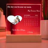 Personalized calendar with a photo of a mother and child, text 'My Forever Hero', and a wooden base on a red background.