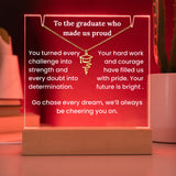 Decorative plaque with a graduation cap design and motivational text on a wooden base.