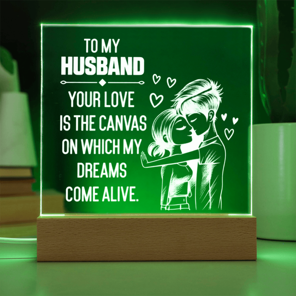 A rectangular LED acrylic night light on a wooden base, glowing green with white text that reads, 'TO MY HUSBAND YOUR LOVE IS THE CANVAS ON WHICH MY DREAMS COME ALIVE,' plus a couple illustration and small hearts.