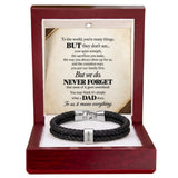A black braided leather bracelet with a silver-toned magnetic clasp and a small engraved name tag, displayed inside an open reddish-brown wooden gift box. The box contains a printed memorial message card addressed to a father.