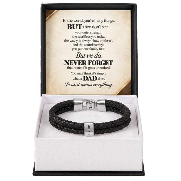 A black braided leather bracelet with silver-toned hardware displayed inside an open gift box. The box has a white interior and a black outer frame, with a printed message card inside the lid that reads 'But we.