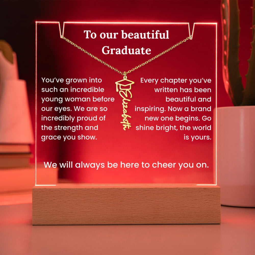 Graduation-themed necklace with engraved message on a wooden stand with red background