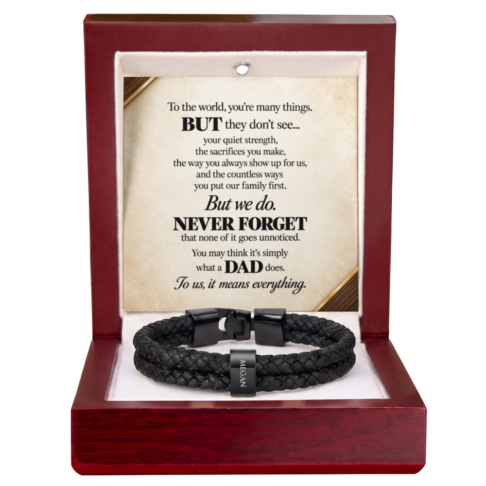 A black braided cord bracelet with a silver-toned metal clasp engraved with 'DAD', presented inside an open dark red wooden gift box. The box features a white insert with a sentimental poem for Dad printed on it.