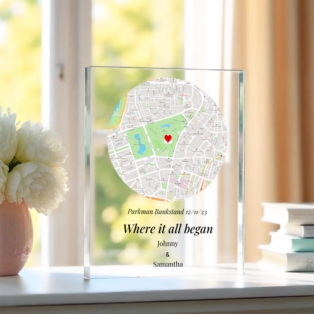 Personalized map in a glass frame on a windowsill with flowers and books in the background.