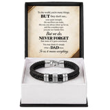 A black braided leather bracelet with silver metal accents engraved with 'DAD', 'HONOR', and 'LOVE', presented in a white box insert with a black outer frame and a sentimental message card inside.