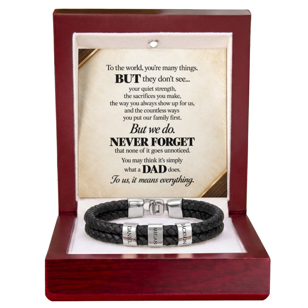 A black braided cord bracelet with silver engraved letter beads and a silver magnetic clasp, presented inside an open dark red wooden gift box. The box contains a printed message card for Dad.