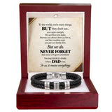 A black braided cord bracelet with silver engraved letter beads and a silver magnetic clasp, presented inside an open dark red wooden gift box. The box contains a printed message card for Dad.