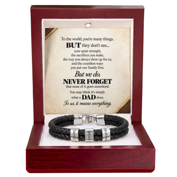 A black braided cord bracelet with silver engraved letter beads and a silver magnetic clasp, presented inside an open dark red wooden gift box. The box contains a printed message card for Dad.