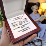 Necklace with a sentimental message card held by a hand, with a blurred background of a person reading a book.