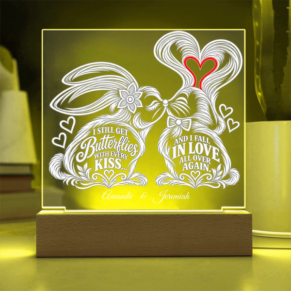 Personalized acrylic LED light box featuring two kissing rabbits with hearts and custom text, displayed on a wooden base with warm yellow lighting.