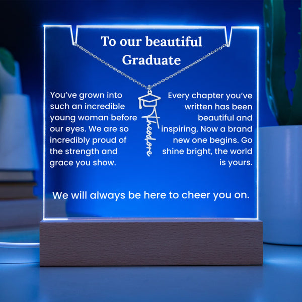 Neon sign with graduation message on a wooden base against a blue background