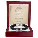 A black braided leather bracelet with silver-toned metal bands engraved with 'HONOR' and 'LOVE', presented inside an open reddish-brown wooden gift box with a white insert and a sentimental quote card.