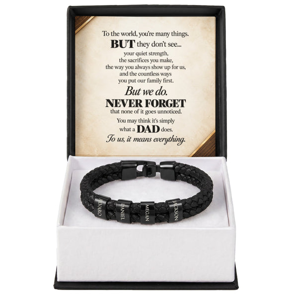 A black braided cord bracelet with silver-toned nameplates engraved with 'DAD' and biblical verses, presented in a white box with a black outer frame and a sentimental message card inside.