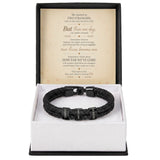 A black braided leather bracelet with silver-toned metal accents and engraved names, presented in an open white gift box with a black outer base. The inside lid features a printed romantic message card.