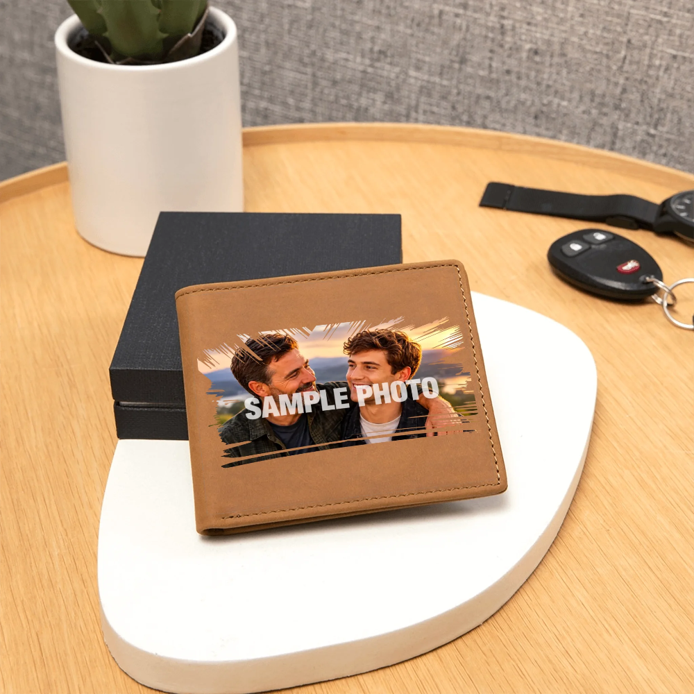 A brown leather bifold wallet with a custom photo print and 'SAMPLE PHOTO' text, displayed on a white decorative tray on a wooden table next to a black box and car keys.