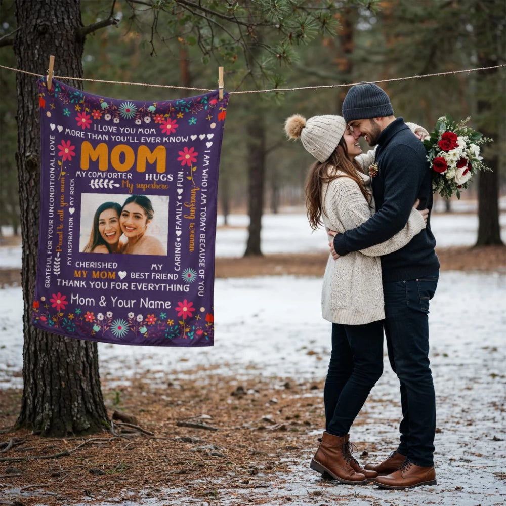Couple embracing outdoors with a personalized blanket featuring text and images of two women.