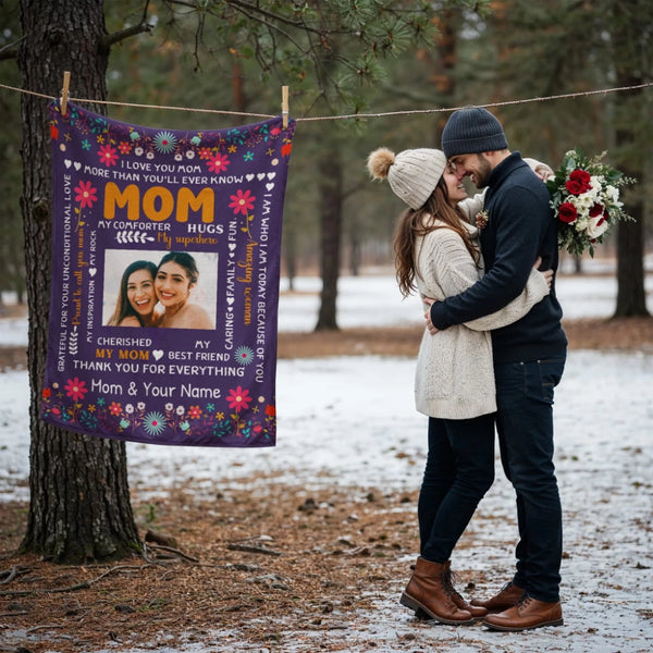 Couple embracing outdoors with a personalized blanket featuring text and images of two women.