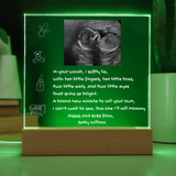 Luminous green sign with ultrasound image and text on a wooden stand.