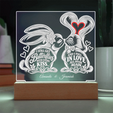 A personalized acrylic LED light sign on a wooden base, featuring two rabbits kissing with decorative white line art and text that reads 'I STILL GET Butterflies WITH EVERY KISS.