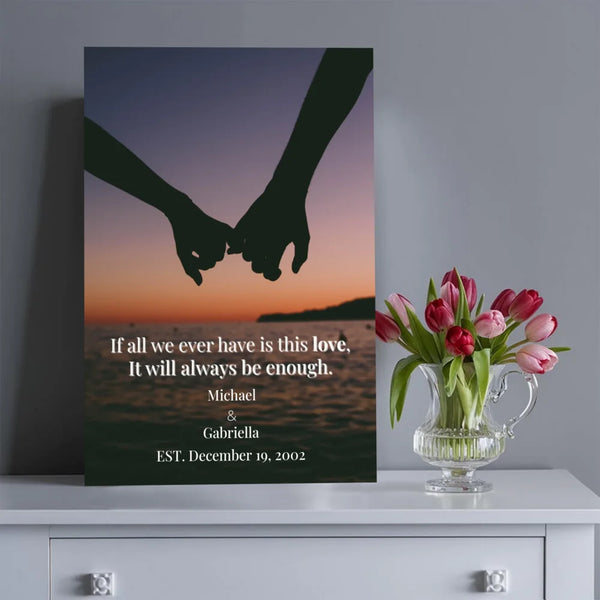Canvas print with silhouette of holding hands and romantic quote, placed on a surface with a vase of flowers.