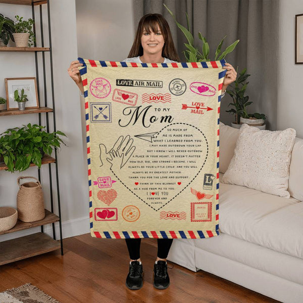 Woman holding a decorative blanket with 'Love to Mom' text in a living room setting.