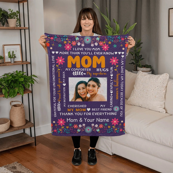 Woman holding a personalized blanket with floral design and text in a living room.