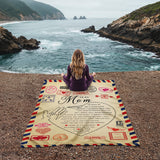 Person sitting on a blanket with a personalized message by the ocean